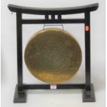 An Eastern embossed brass dinner gong, within an ebonised surround, w.43cmCondition report: Table