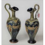 A pair of Royal Doulton stoneware ewers, each on a mottled blue/green ground with glazed floral