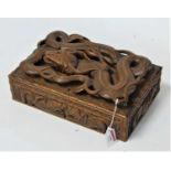 An Indian carved hardwood table cigarette box, the hinged cover carved with a sinuous beast, width