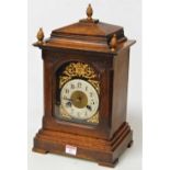 A late 19th century continental oak cased mantel clock, having brass arched dial with cherub