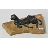 A contemporary bronzed resin sculpture of a big cat in reclining pose, on rock plinth, incised David