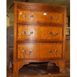 A mahogany and crossbanded serpentine front chest of three long drawers, having upper brushing