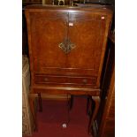 A 1930s walnut and figured walnut double door drinks cabinet, having a mirrored interior over single