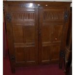 An antique joined oak double door side cupboard, having exposed and shaped iron hinges with later