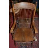 An early 20th century oak stickback elbow chair with a dished seat, width 60cm