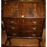 An early 20th century mahogany slope front three drawer writing bureau on shell capped cabriole