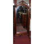 A contemporary carved and pierced hardwood arched top bevelled cheval mirror, raised on turned and