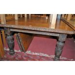 A circa 1900 heavily carved floral oak round cornered extending dining table, having a wind-out