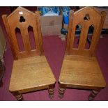 A pair of Victorian Gothic revival oak panel seat hall chairs, each having pierced backsCondition