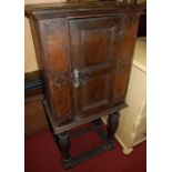 An antique oak cupboard on stand, of small proportions, having twin panelled door with exposed