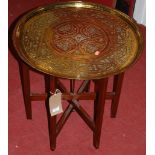 An Eastern engraved circular brass topped folding Benares table, dia. 58cm