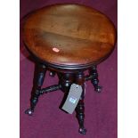 An early 19th century mahogany circular revolving stool, raised on turned and ring turned supports