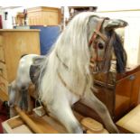 A contemporary child's dapple grey rocking horse with tan leather saddle, the beech stand with