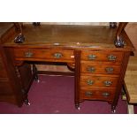 An Edwardian walnut single pedestal kneehole writing desk, having a tan rexine inset surface over an