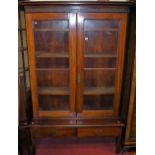 An early 20th century mahogany double door glazed bookcase, raised on adapted two drawer squat base,