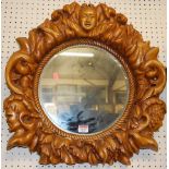 A contemporary hardwood carved and floral mask decorated circular wall mirror, dia.50cm