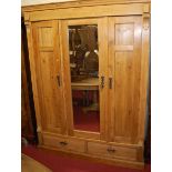 A French stained pine three door armoire, having mirrored centre door over twin short lower drawers,