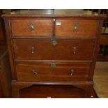 An antique oak and mahogany low chest of two short over two long drawers, having brass teardrop