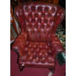 A tan leather button studded upholstered wingback scroll armchair, raised on cabriole forelegs (with