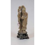 A Chinese carved soapstone figure of Shou Lao, carved holding a peach and ancient rootwood staff, on