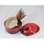 A graduated set of four Le Creuset red enamelled saucepans and covers (one cover missing)