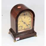 A 1920s mahogany cased dome topped mantel clock having a brass arched dial with engraved