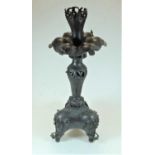 An Eastern spelter table candle stand, having a pierced top above a lily-pad stem, to a triform base