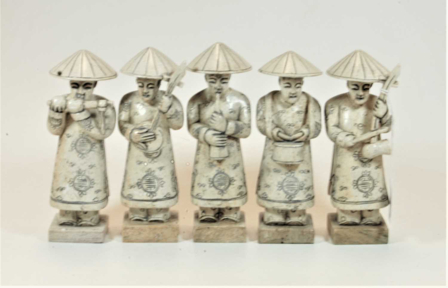 A set of five carved stone figures, each in the form of a male musician playing a different