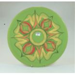 A large Poole Pottery Delphis charger on a green ground with red, orange and yellow floral