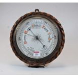 An early 20th century aneroid barometer housed within a carved oak ropetwist surround, dia. 27cm