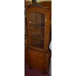 A contemporary figured walnut freestanding corner cupboard, having glazed upper door