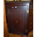 An early 19th century provincial oak and chequer strung single hanging door corner cupboard