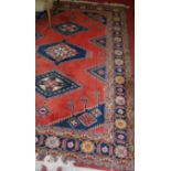 A Persian woollen red ground Shiraz rug, the central medallions within trailing tramline borders,