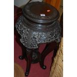 A Chinese ebonised and floral relief carved circula urn stand, having a Greek key decorated top over