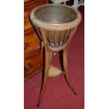 An Edwardian faded mahogany and inlaid circular plant stand, having removable brass liner (with