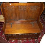 An oak three-panelled box seat settle, the panels with Gothic influenced floral arch relief