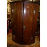 A circa 1800 provincial mahogany double door bowfront hanging corner cupboard