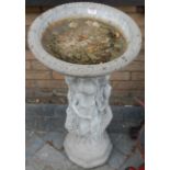 A reconstituted stone pedestal bird bath, the circular top supported on a pedestal in the form of