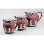 A set of three Wedgwood 'Red' jasperware graduated jugs, each decorated with a floral swag frieze