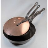 A pair of 19th century copper saucepans, each having iron handles and with loose covers, together