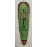 A modern tourist tribal style wall mask in the form of an elongated head with a beaded lizard