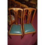 A set of four Edwardian beech splatback dining chairs, each having green leather upholstered drop-in