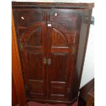 An early 19th century north country panelled oak double door hanging corner cupboard, having