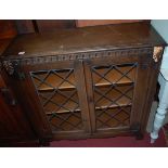 A contemporary oak and lead glazed low double door bookcase, w.92cm