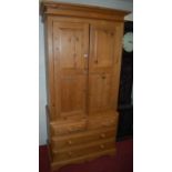 A modern pine double door wardrobe, the enclosed hanging space over base fitted with two short