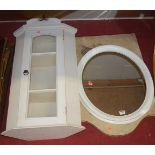 A modern white painted oval wall mirror, modern single gate fold screen, and a painted hanging