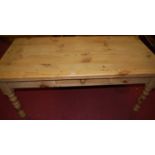 A modern pine round cornered farmhouse kitchen table, having single side frieze drawer and raised on