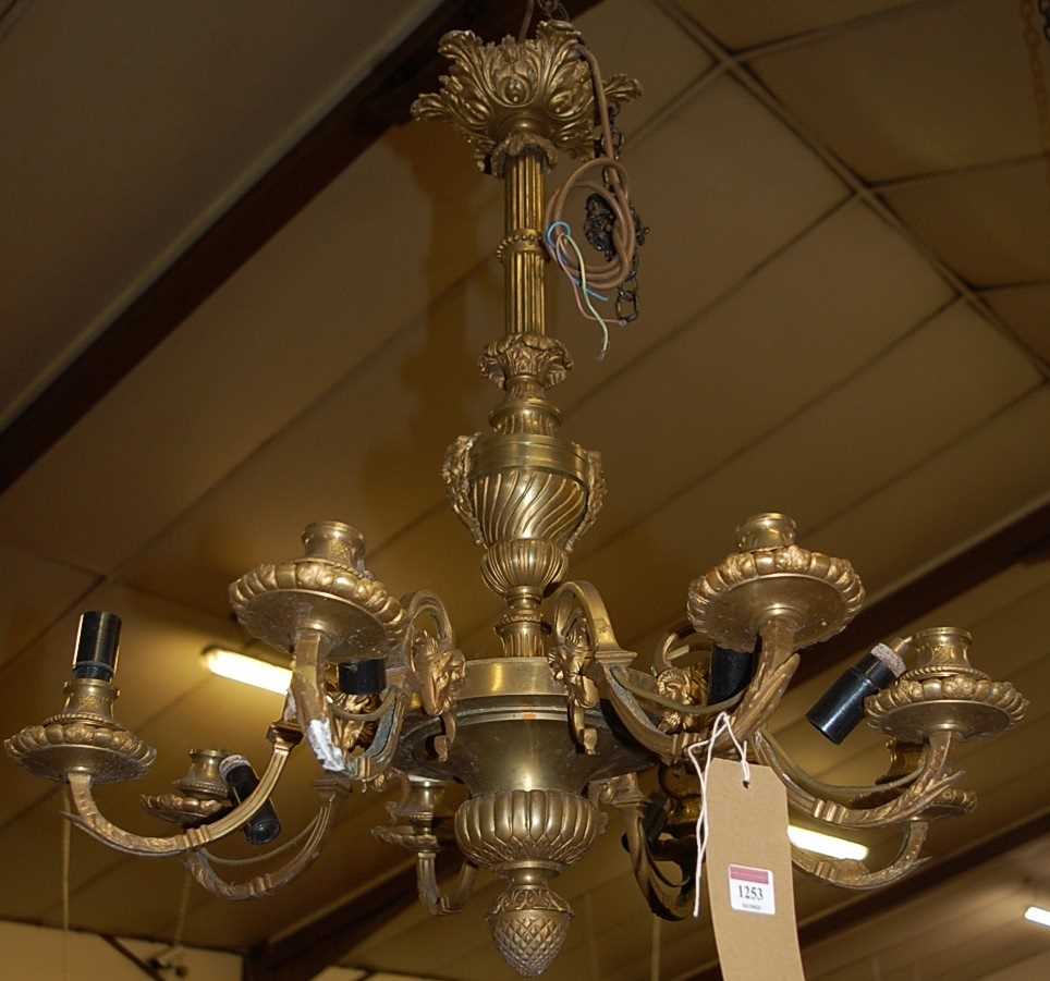 A French cast and gilt brass hanging eight light electrolier, with rams head masked scroll branches,