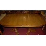 A contemporary oak twin pedestal round cornered extending dining table, having pull-out action and