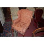 A contemporary red floral upholstered wing back scroll armchair, raised on cabriole forelegs,